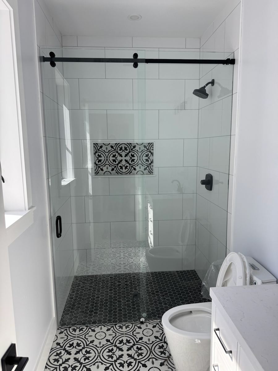Black and white modern luxury zero-entry shower with frameless barn door enclosure, St. Augustine Beach FL